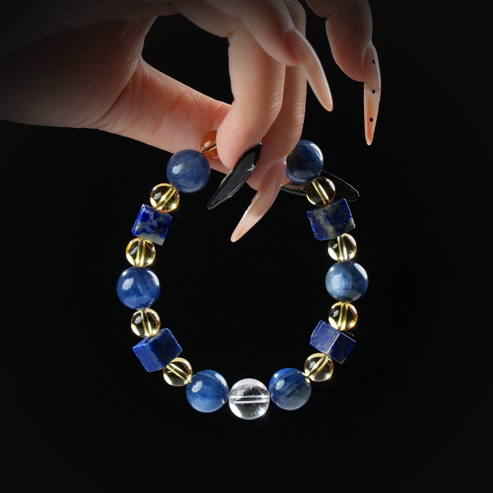 Kyanite, lapis lazuli, and golden rutile quartz beaded bracelet with square lapis stones, held by hand on black background for wisdom and energy flow.