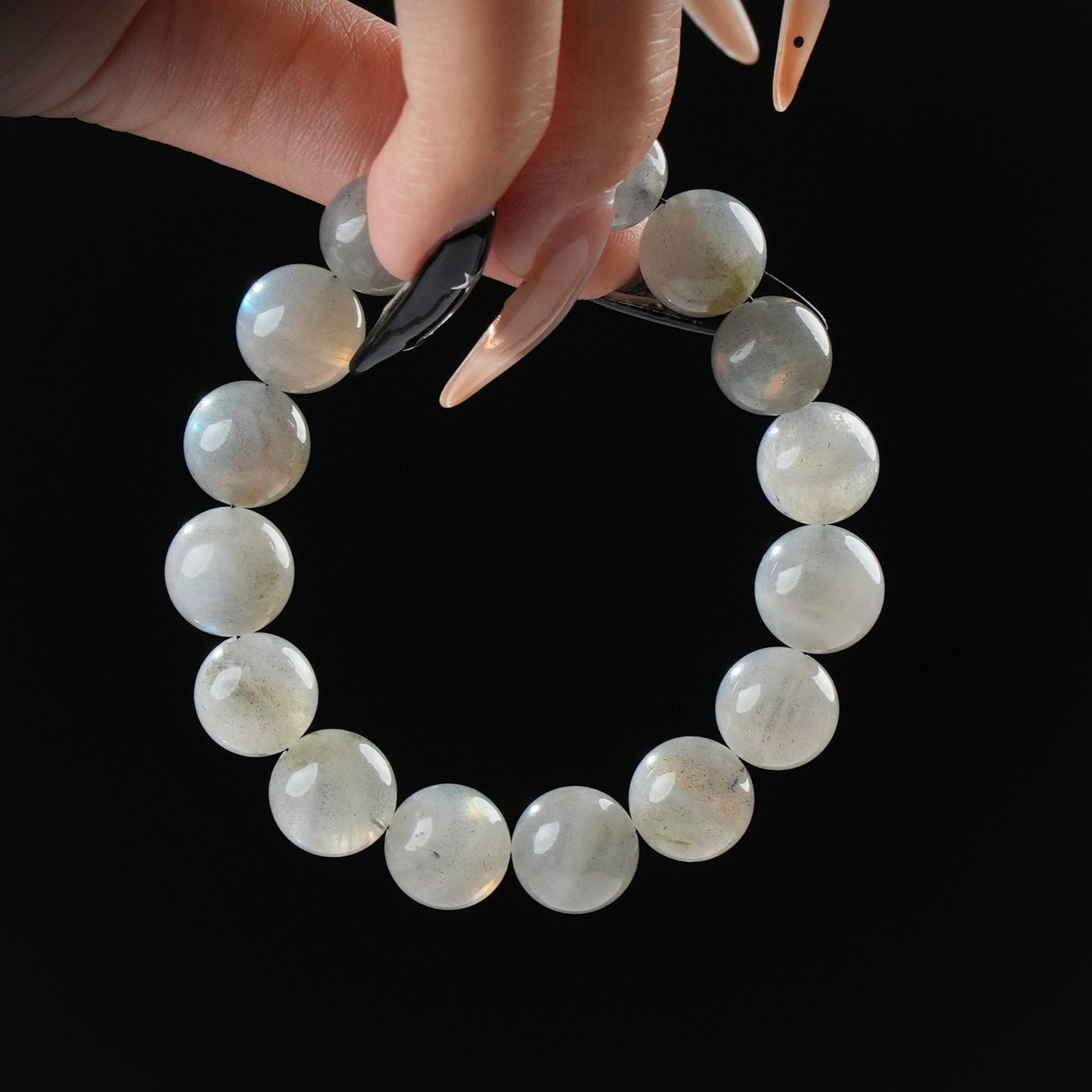 Labradorite beaded bracelet with subtle flash, held by hand on black background for intuition and transformation.