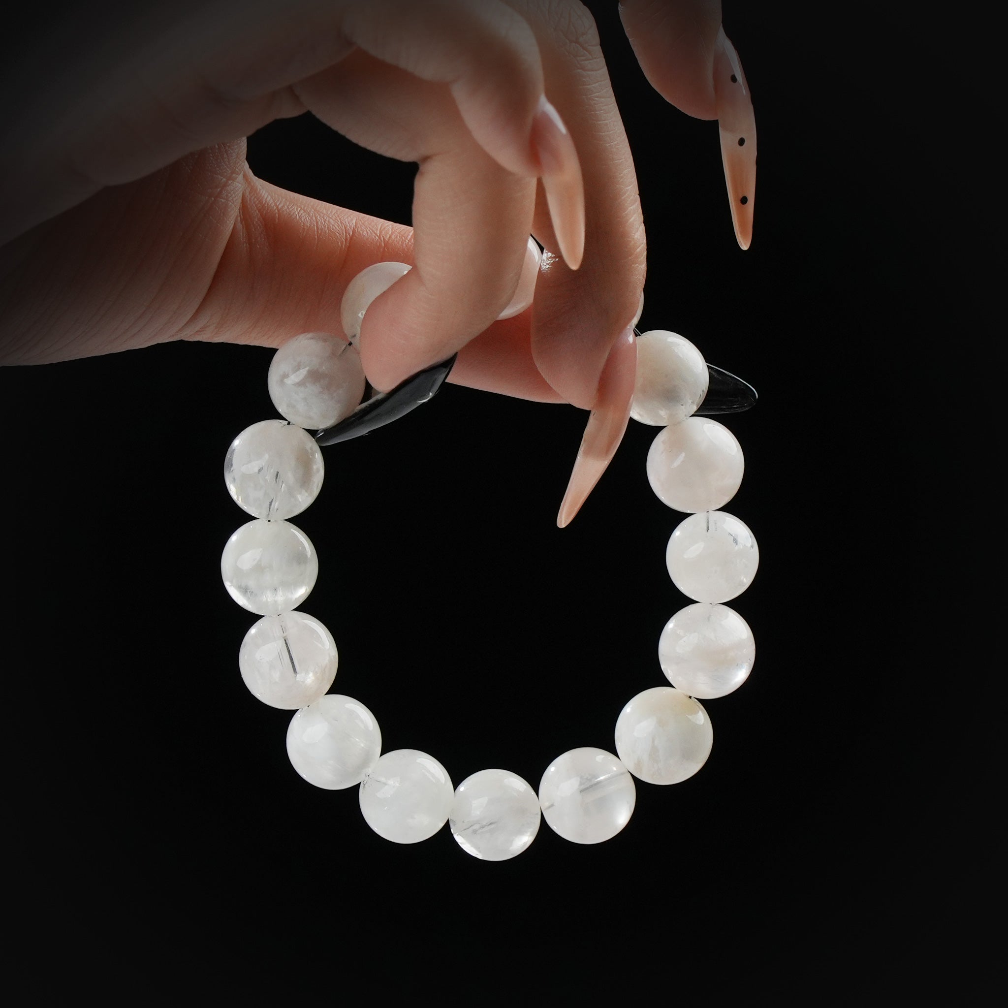 White moonstone beaded bracelet with soft glow, held by hand on black background for emotional balance and feminine energy.