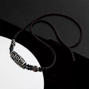 The Tibetan Nine-Eyed Dzi bead necklace rests on a reflective black surface, highlighting the polished beads and their distinct patterns.