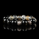 This image shows a polished bracelet composed of glossy 12mm beads, including transparent Clear Quartz, golden-hued Citrine, deep black Obsidian, and shimmery Silver Obsidian. The bracelet is displayed against a black reflective background, enhancing the brilliance and contrast of each stone’s natural color and texture.