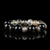 This image shows a polished bracelet composed of glossy 12mm beads, including transparent Clear Quartz, golden-hued Citrine, deep black Obsidian, and shimmery Silver Obsidian. The bracelet is displayed against a black reflective background, enhancing the brilliance and contrast of each stone’s natural color and texture.