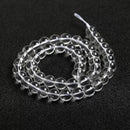 Looped natural quartz beads strung together, highlighting their uniformity and transparency.