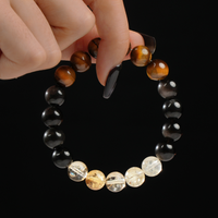 A person gently holds a gemstone bracelet composed of 12mm beads, showcasing the radiant blend of Tiger’s Eye, luminous Citrine, and reflective Silver Sheen Obsidian stones.