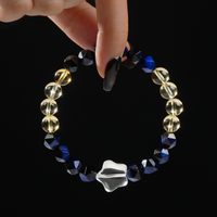 This bracelet features a minimalist yet elegant design combining transparent round Clear Quartz beads with faceted navy blue Tiger's Eye stones. The contrast of clarity and depth creates a refined, modern aesthetic, beautifully captured while being held delicately between two fingers.