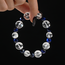 This bracelet features a minimalist yet elegant design combining transparent round Clear Quartz beads with faceted navy blue Tiger's Eye stones. The contrast of clarity and depth creates a refined, modern aesthetic, beautifully captured while being held delicately between two fingers.