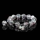 A bracelet of soft pink and clear crackled beads, sweet and gentle in tone, accented with a shimmering butterfly charm at its center.