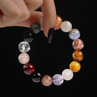 A close-up of a hand holding a circular bracelet made of various vibrant crystals, showing off each bead’s unique color and pattern. 