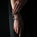 Hand model displaying a beaded bracelet made of round clear quartz and faceted deep blue lapis lazuli, elegant and minimal against a dark fabric backdrop.