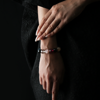 A woman wearing a multistone crystal bracelet featuring amethyst, rose quartz, tiger’s eye, red rutilated quartz, chalcedony, citrine, snow phantom, moonstone, aquamarine, clear quartz, strawberry quartz, garnet, and flower agate.