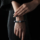 A beaded bracelet with deep purple Amethyst, soft blue Aquamarine, and clear White Crystal stones, elegantly worn on the wrist.
