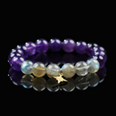 A round-bead bracelet featuring vibrant purple Amethyst and shimmering Labradorite stones, accented with a delicate gold star charm, displayed on a glossy black reflective surface.