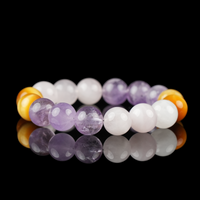 A handcrafted bracelet composed of polished amethyst, soft rose quartz, and golden yellow tiger eye beads. The natural stones are arranged in a gradient of purple, pink, and honey tones, beautifully displayed against a glossy black background.