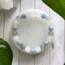 Bracelet placed on a white crystal dish with natural background, showcasing translucent and pastel stones that evoke calmness and spiritual clarity.