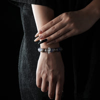 A bracelet made of soft blue Aquamarine and clear White Crystal beads, worn on the wrist with a black lace dress.