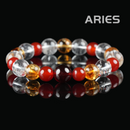 Flat lay of Aries zodiac healing crystal bracelet made with red agate, yellow citrine, and clear quartz beads on black background.