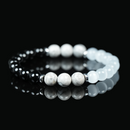 Close-up image of a black obsidian and cat’s eye gemstone bracelet with polished white and black beads, symbolizing protection, intuition, and balance.