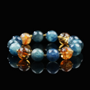 A vibrant gemstone bracelet featuring alternating beads of deep blue Kyanite and golden Citrine, accented with small gold spacers, displayed on a glossy black surface.
