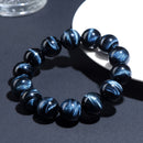 View of bracelet under angled natural light, beads arranged on dark surface with dynamic reflections enhancing their depth and energy.