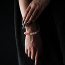 A crystal bracelet worn on the wrist, made of orange moonstone, rose quartz, aquamarine, amethyst, and blue sandstone.