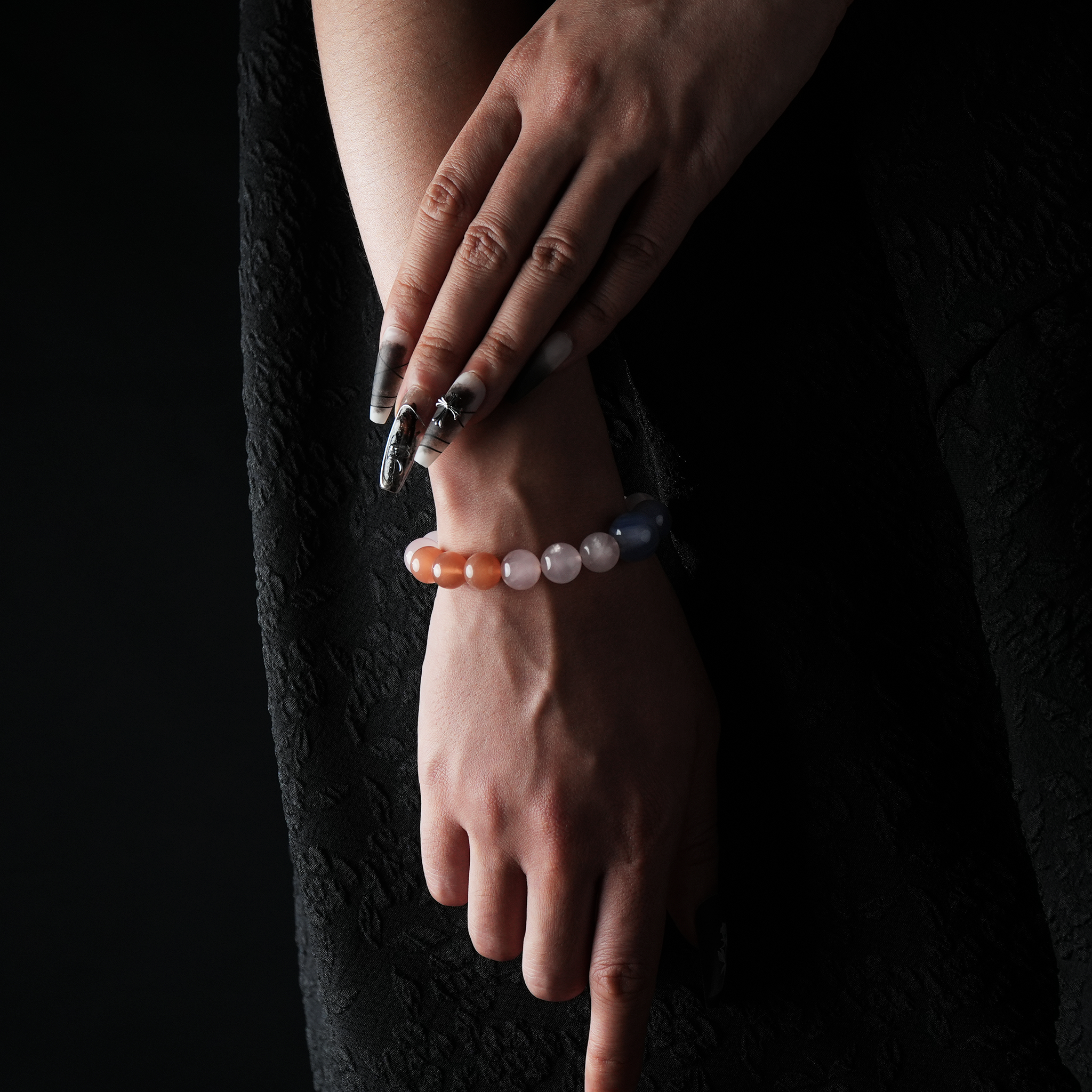 A crystal bracelet worn on the wrist, made of orange moonstone, rose quartz, aquamarine, amethyst, and blue sandstone.
