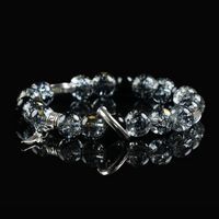 Black rutilated quartz bracelet with celestial-themed silver charms and hook clasp, displayed on reflective surface for spiritual protection.