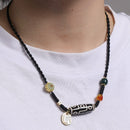 A detailed view of a Tibetan 9-Eye Dzi Agate necklace showcasing the black and white design of the Dzi bead, complemented by gold and jade accents, highlighting the fine craftsmanship.