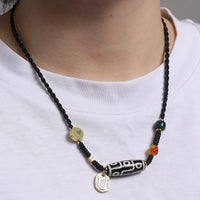 A detailed view of a Tibetan 9-Eye Dzi Agate necklace showcasing the black and white design of the Dzi bead, complemented by gold and jade accents, highlighting the fine craftsmanship.