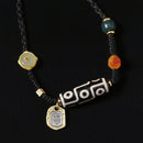 A Tibetan Dzi bead necklace featuring the 9-eye pattern, symbolic of protection and good fortune. The necklace is worn by a person, with gold and gemstone accents.