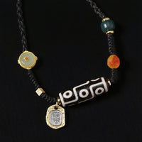A Tibetan Dzi bead necklace featuring the 9-eye pattern, symbolic of protection and good fortune. The necklace is worn by a person, with gold and gemstone accents.