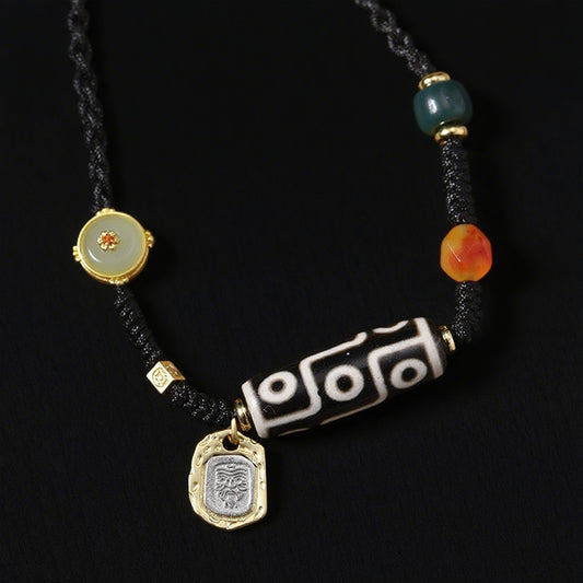 A Tibetan Dzi bead necklace featuring the 9-eye pattern, symbolic of protection and good fortune. The necklace is worn by a person, with gold and gemstone accents.