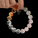 Hand-held view of a multigem bracelet, highlighting the shimmer and tones of each natural bead.