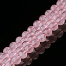 A detailed close-up of polished rose quartz beads arranged in tight rows. The beads are semi-transparent with a soft pink hue, showing natural inclusions and internal textures that highlight their authenticity.