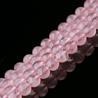 A detailed close-up of polished rose quartz beads arranged in tight rows. The beads are semi-transparent with a soft pink hue, showing natural inclusions and internal textures that highlight their authenticity.