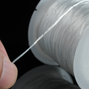 A close-up view of a hand gently pulling the flat elastic thread from the spool, showcasing the thread’s stretch and durability.
