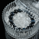A gemstone bracelet placed in a glass bowl filled with cleansing crystals, symbolizing energy recharging.