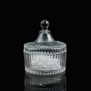A clear ribbed glass charging bowl with a lid, placed on a reflective black background, filled with clear crystal chips.