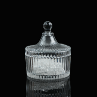 A clear ribbed glass charging bowl with a lid, placed on a reflective black background, filled with clear crystal chips.