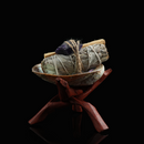 A smudge bundle with amethyst crystal placed in a shell bowl with wooden stand, styled against a black background.