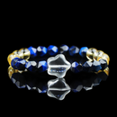 A gemstone bracelet featuring deep blue lapis lazuli beads, golden yellow citrine beads, and a unique carved clear quartz centerpiece shaped like a flowing cloud or abstract flower. The beads are faceted for extra brilliance, with a polished and luxurious finish set against a black reflective background.