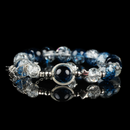 A celestial-inspired bracelet featuring galaxy energy beads in deep blue and crackled clear tones, accented with silver star spacers and a central orb framed in silver. The reflective black surface enhances its cosmic and mystical aesthetic.