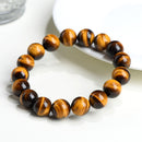 A yellow tiger eye bracelet placed across a white plate, highlighting its smooth texture and glowing stripes.