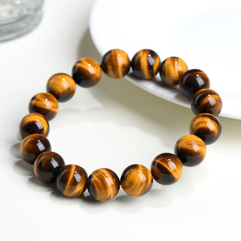 A yellow tiger eye bracelet placed across a white plate, highlighting its smooth texture and glowing stripes.