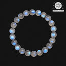 Circular arrangement of a gray moonstone bracelet photographed from above on a matte black background, showcasing the stone’s inner glow and natural inclusions.