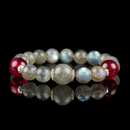 A handcrafted crystal bracelet featuring shimmering grey moonstone beads paired with vivid red garnet accents, beautifully displayed on a reflective black surface.