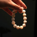 A hand holding snow phantom bracelet in moody lighting, showcasing the ethereal white stones ideal for meditation, healing, and inner clarity.
