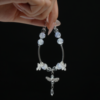 A hand gently displaying a shimmering silver-blue energy bracelet with butterfly charms and a detailed dragonfly pendant, evoking peaceful movement and spiritual clarity.