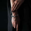 A deep blue crystal bracelet with silver beads and a dangling star charm, worn on the wrist against a black outfit.