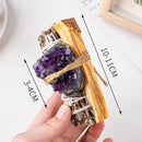 A hand holding a crystal-infused sage and palo santo bundle, showing size dimensions on a white background.