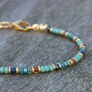 A zoomed-in image of the clasp and end beads of a turquoise anklet with mixed color accents.